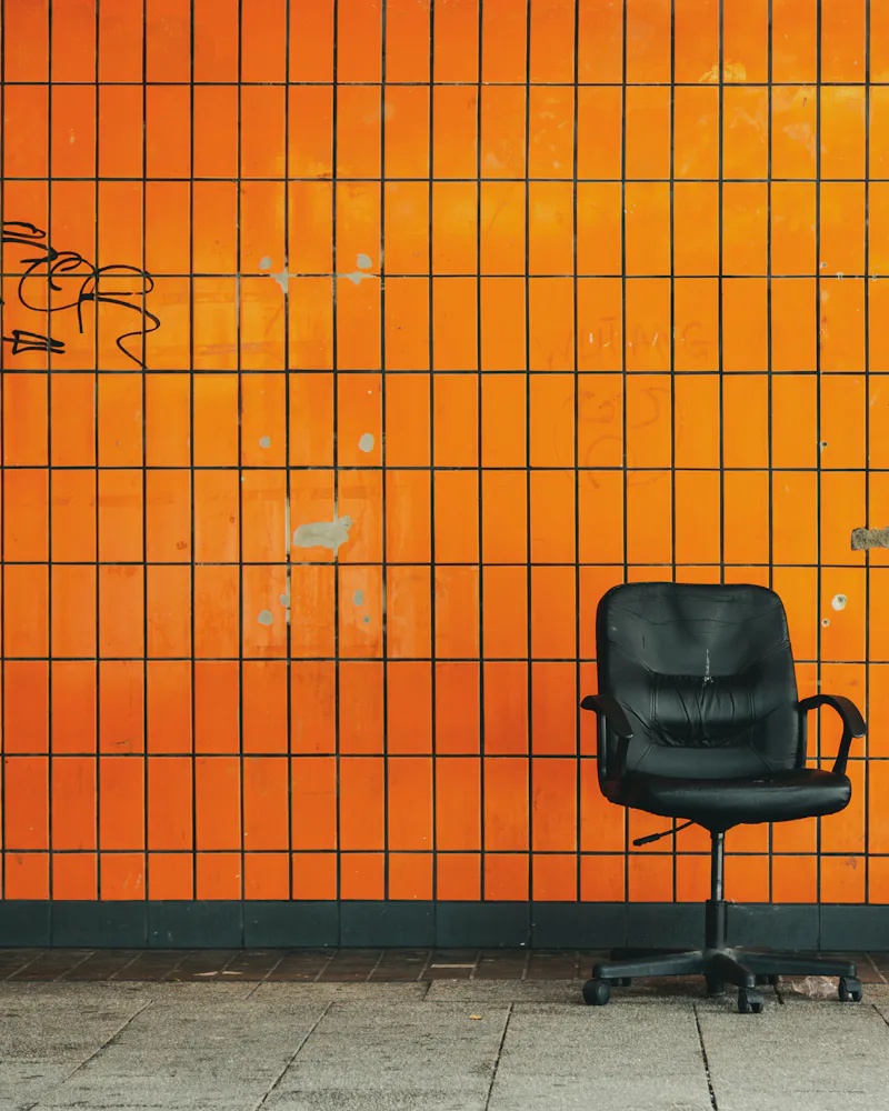 Silla de oficina vacía frente a una pared naranja
